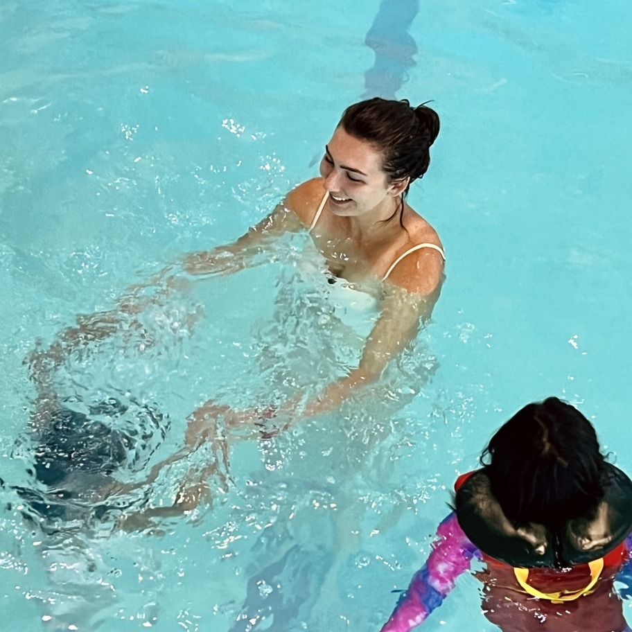 An adult with two kids playing in a pool