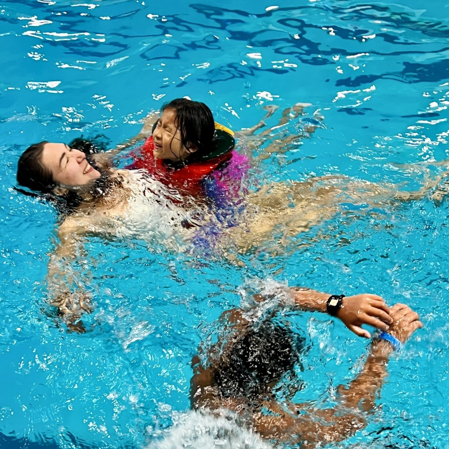 An adult with two kids playing in a pool