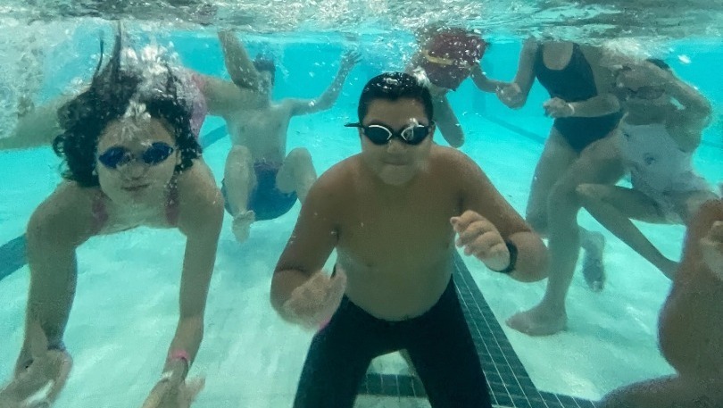 Kids posing for a photo under the water at the pool