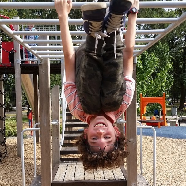 KId hanging upside down on bars at the playground
